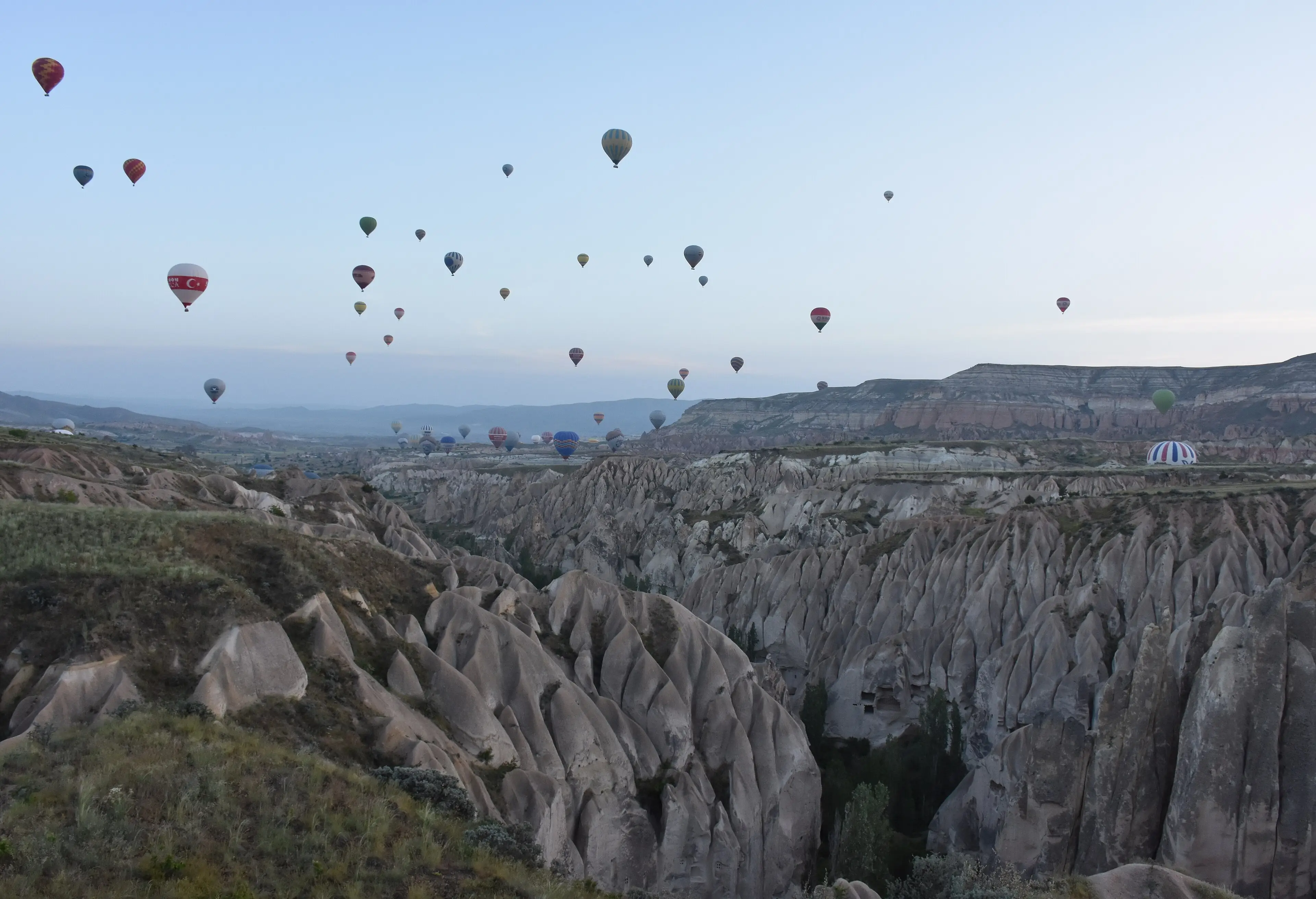 Hot-air balloons drifting over eroded valleys near Göreme at dawn