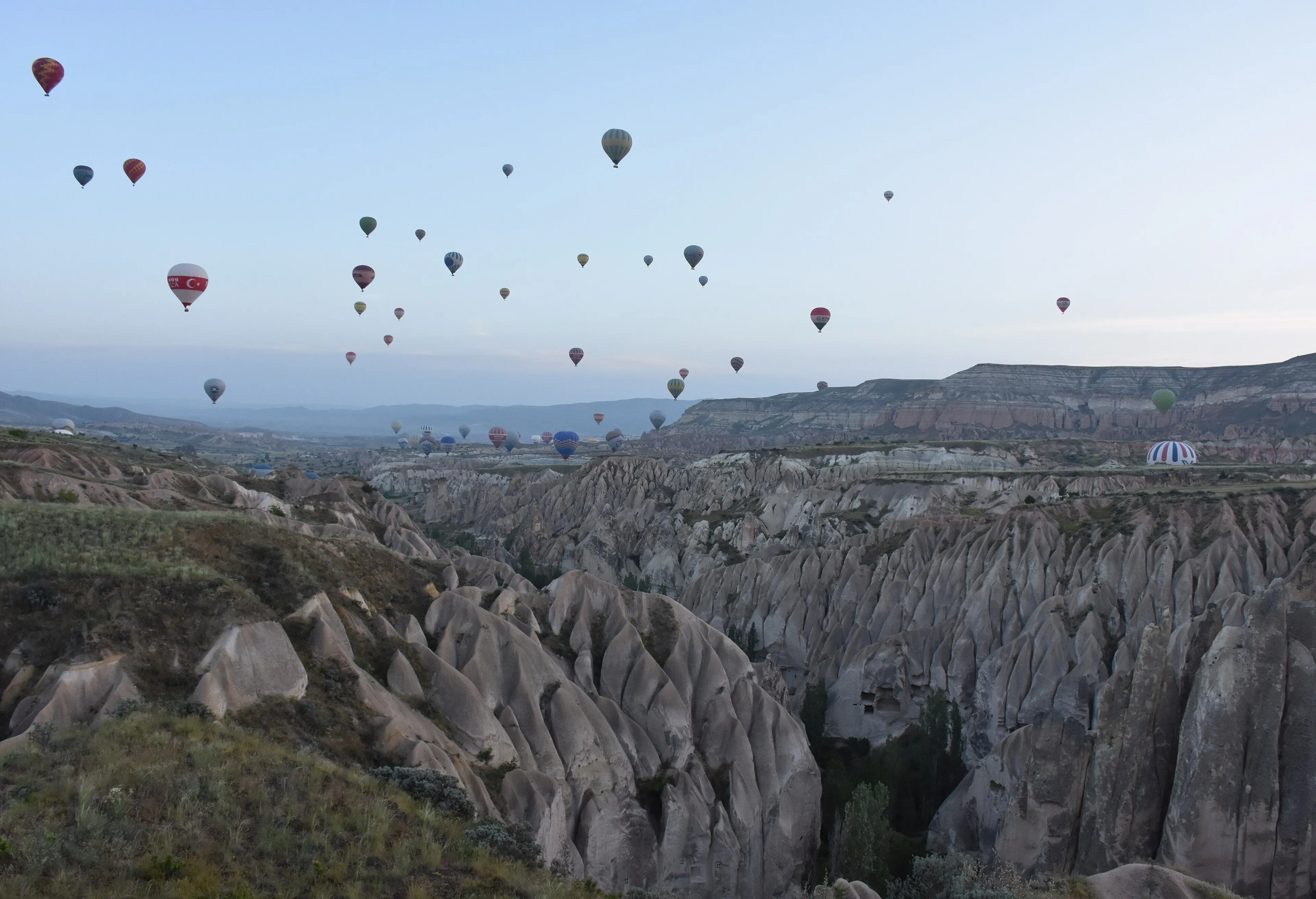 Hot-air balloons drifting over eroded valleys near Göreme at dawn